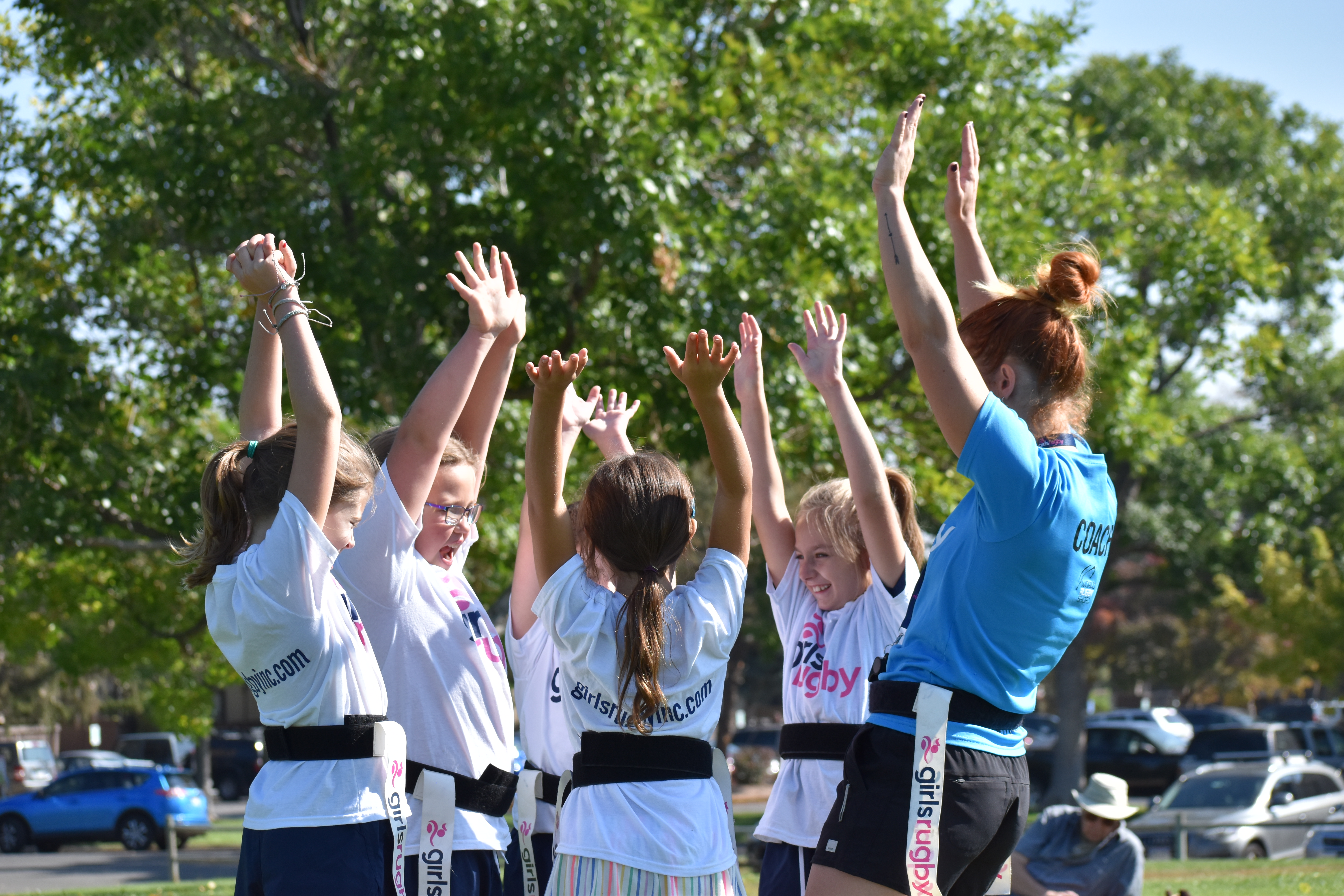 Girls Rugby girls huddled with arms up 